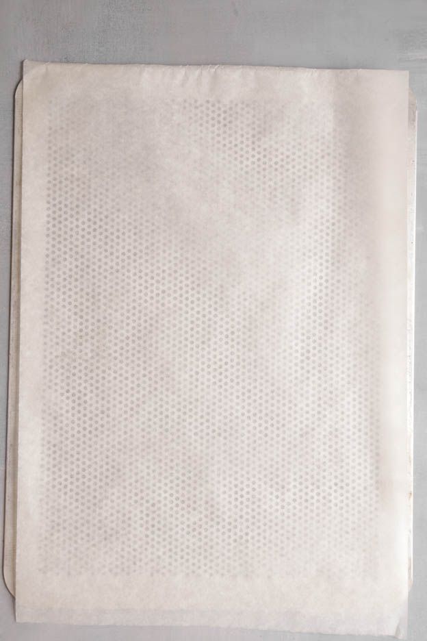 Cut sheet of baking parchment on a grey surface, preparing the summer cakesicles