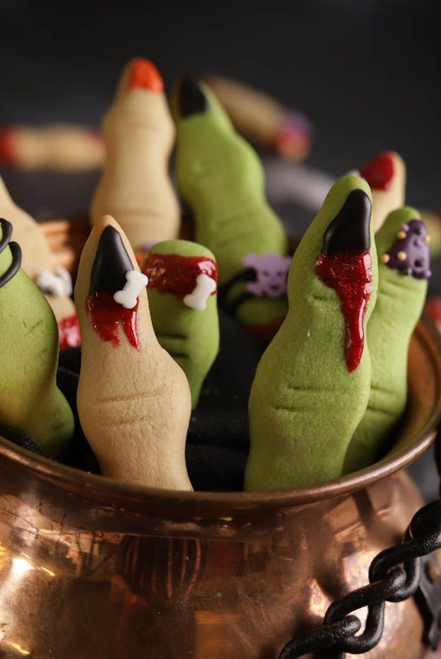 Nahaufnahme eines grünen Hexenfingers mit Totenkopf-Zuckerdeko