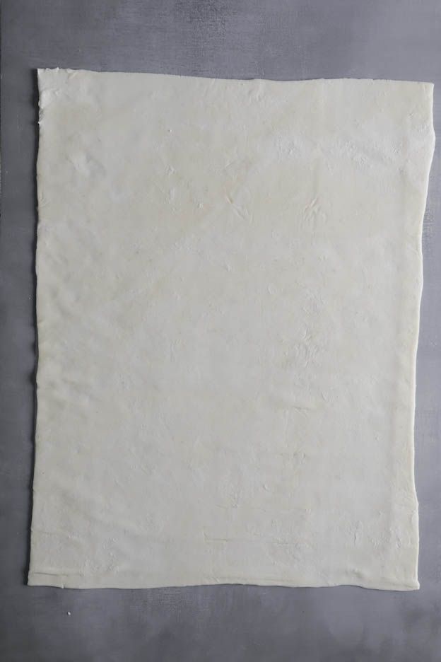 Rolled out rectangular sheet of dough on a grey worktop, base for the pesto flutes