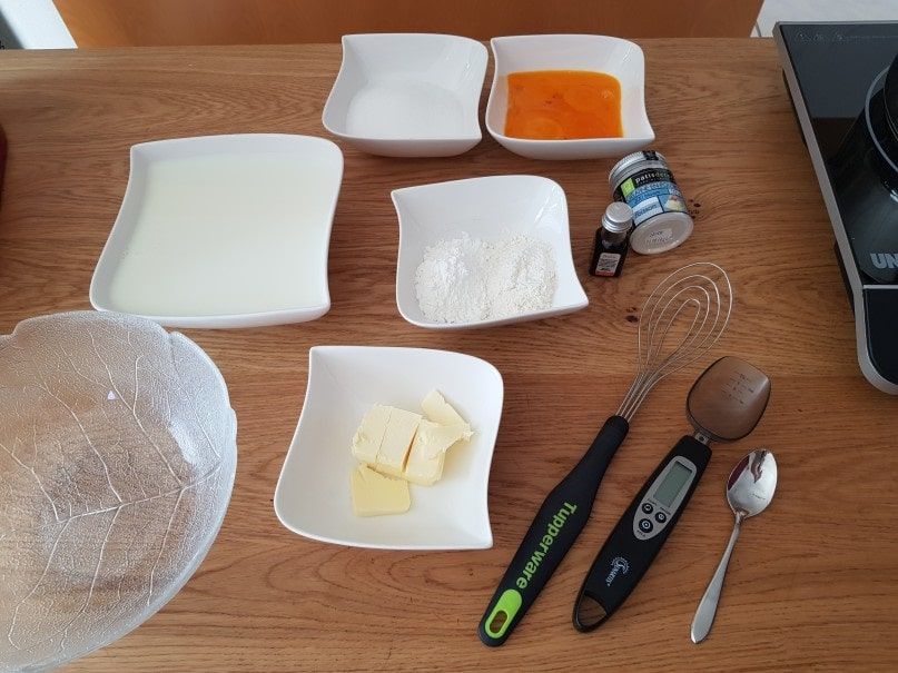 Mise en place for the mille-feuille with milk, orange puree, butter cubes and a spoon scale