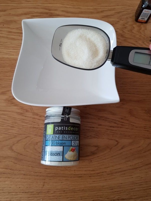 White powder weighed on a digital spoon scale next to a Patisdécor jar