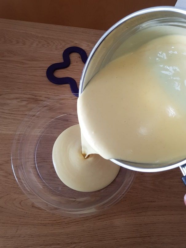 Pale yellow pastry cream poured from the pan into a glass bowl for the cream slice