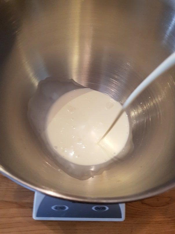 Cream weighed in the stand mixer bowl placed on a digital kitchen scale