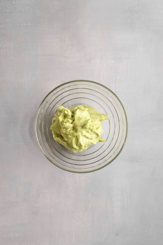 Portion of pale green avocado purée in a glass bowl for the brick tartlets