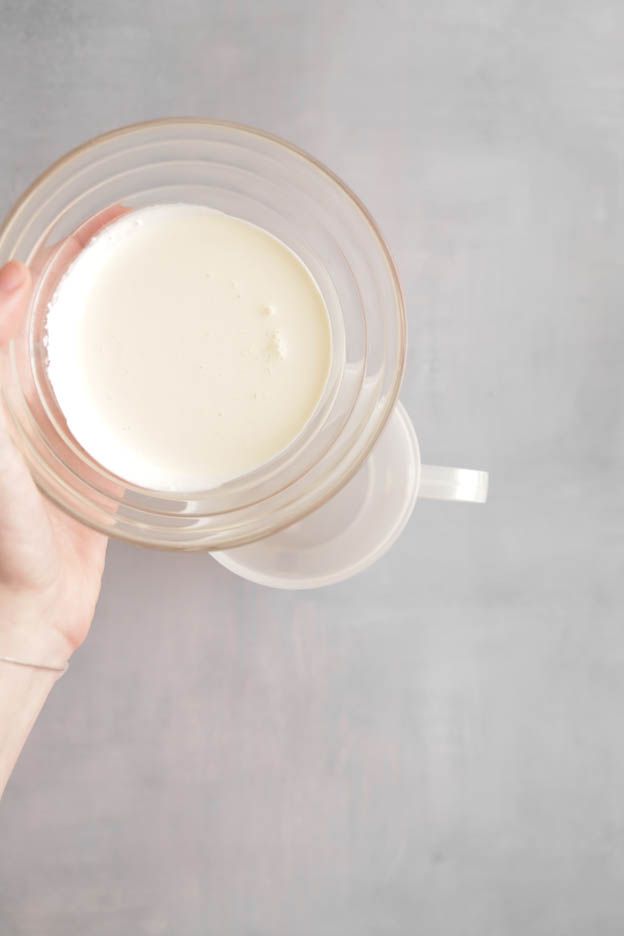 Hand holding a glass jug of cream seen from above for the avocado brick tartlets