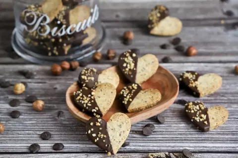 Heart-shaped hazelnut cookies, half coated in chocolate