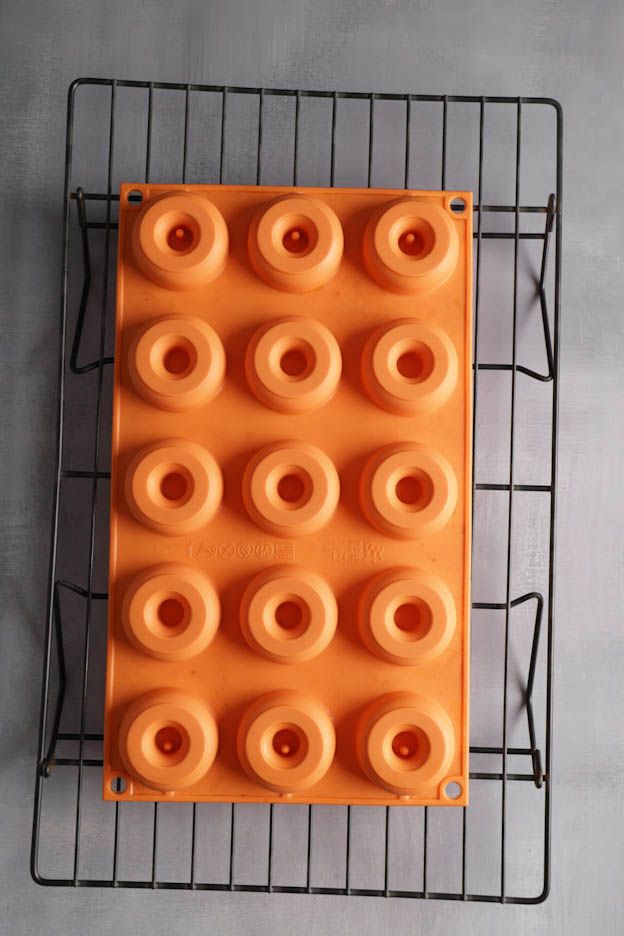 Moule en silicone orange avec 15 cavités à mini-beignets sur la grille à gâteau