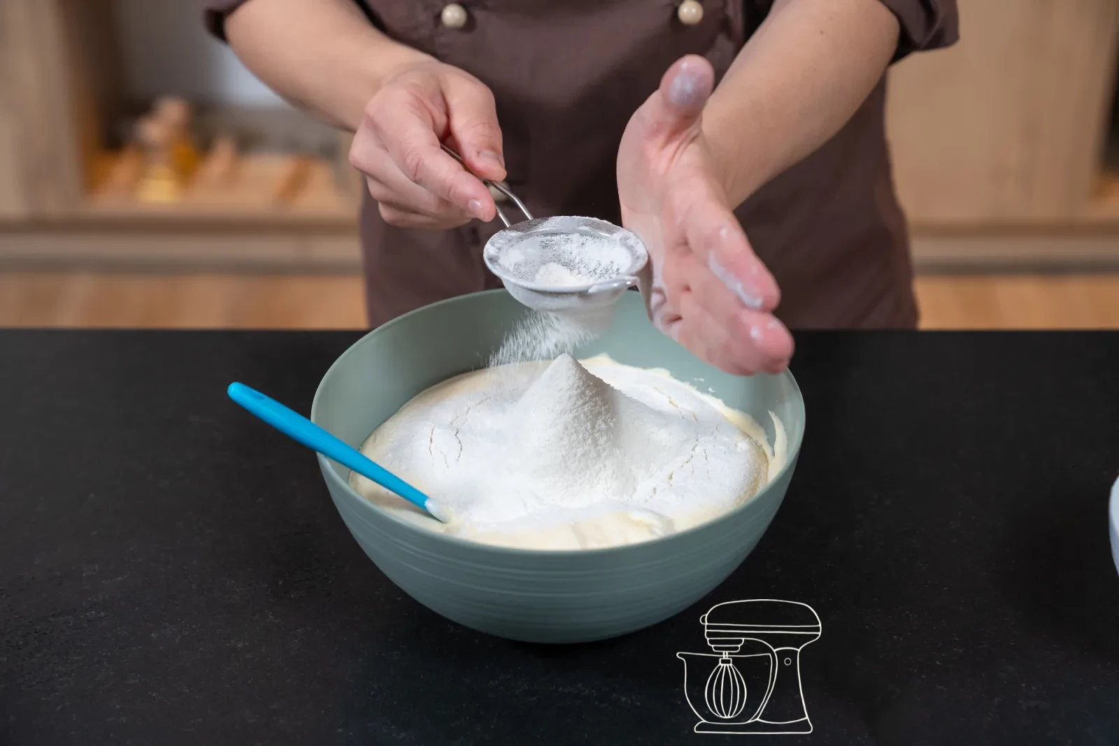 Pale egg-yolk-and-sugar foam in a bowl, with glossy whipped egg white and a sieve of flour beside it