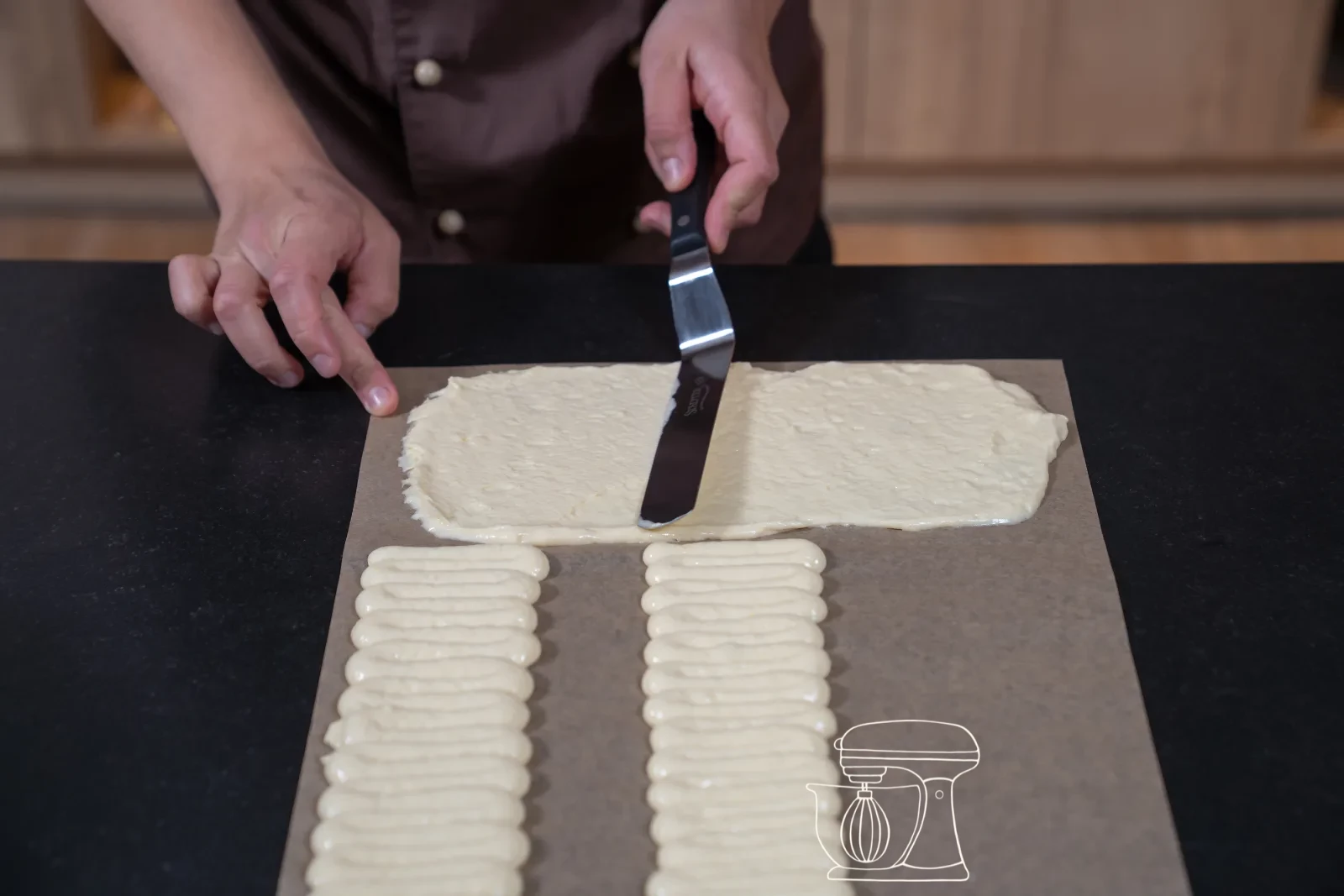 Piping bag forming a zigzag strip of sponge mixture on baking paper, with a smoothed sponge surface beside it