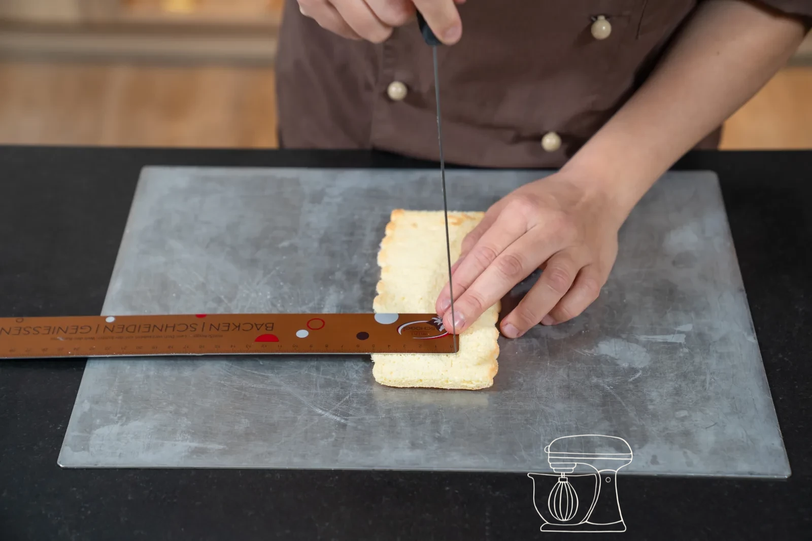 Trimmed sponge strip being set as a ring into a round patisserie mold, with cut-out sponge bases beside it