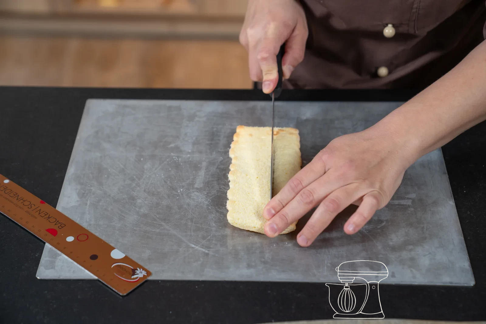 Trimmed sponge strip being set as a ring into a round patisserie mold, with cut-out sponge bases beside it