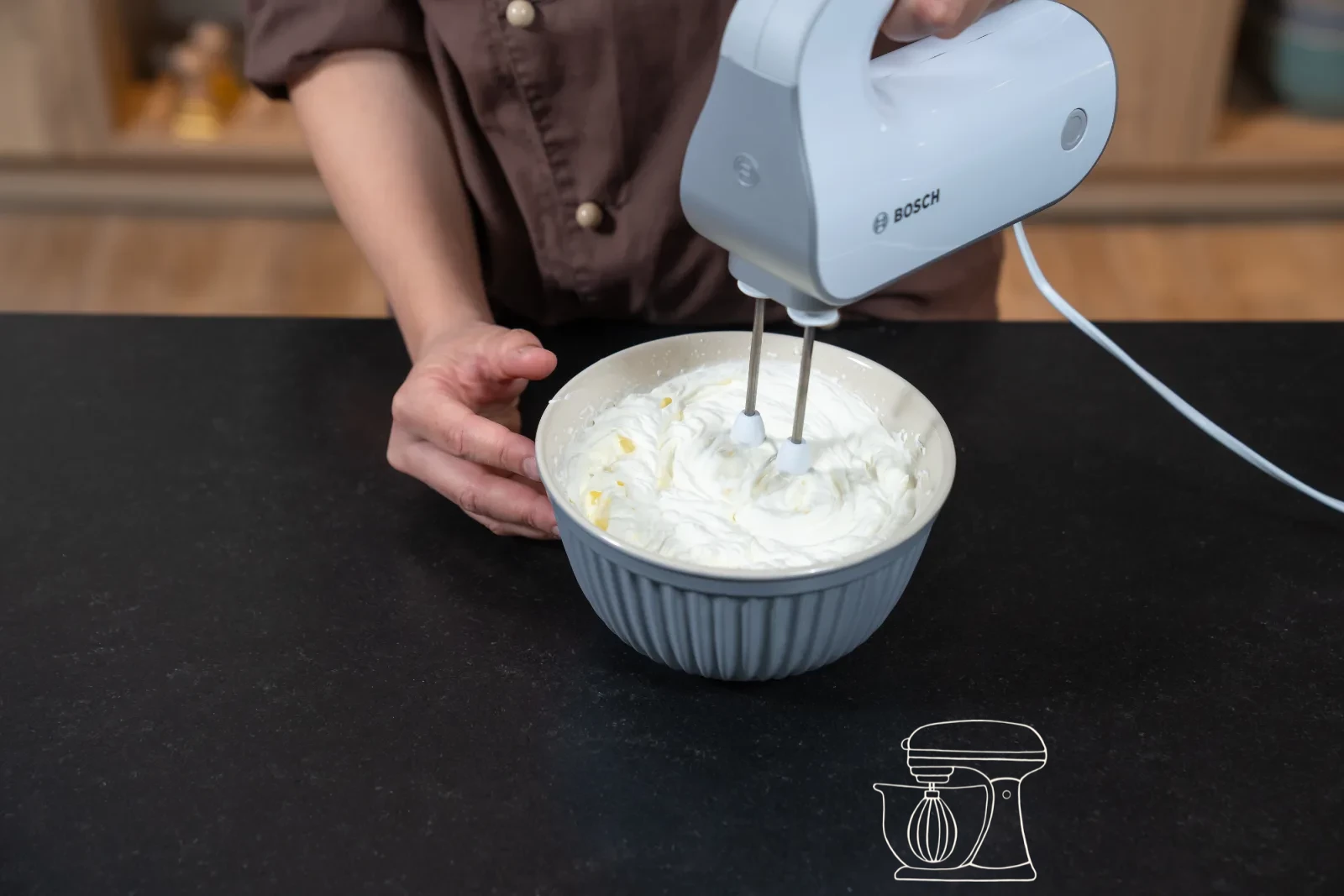 Thickened vanilla cream being stirred in the pot with a whisk, with a bowl and cling film beside it
