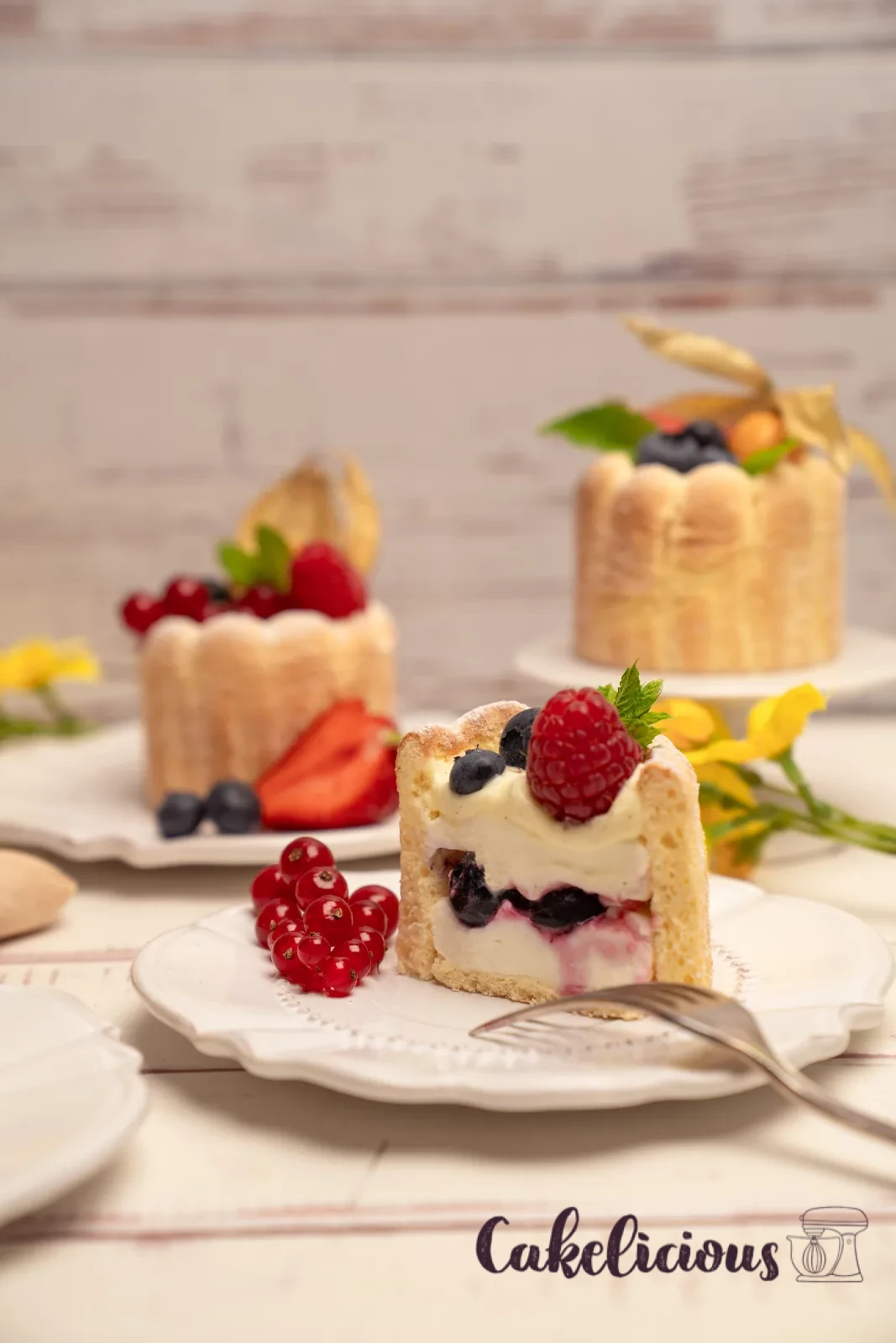 Row of finished charlottes on a stand, with a bowl of mixed berries in the background