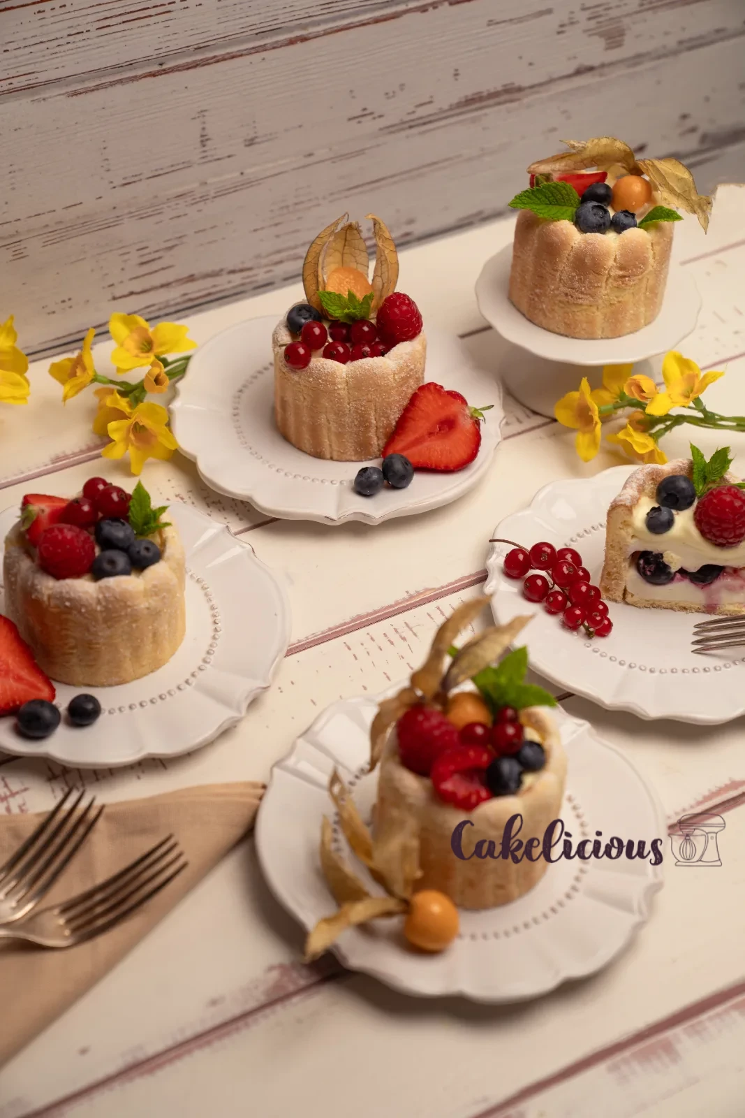 Row of finished charlottes on a stand, with a bowl of mixed berries in the background