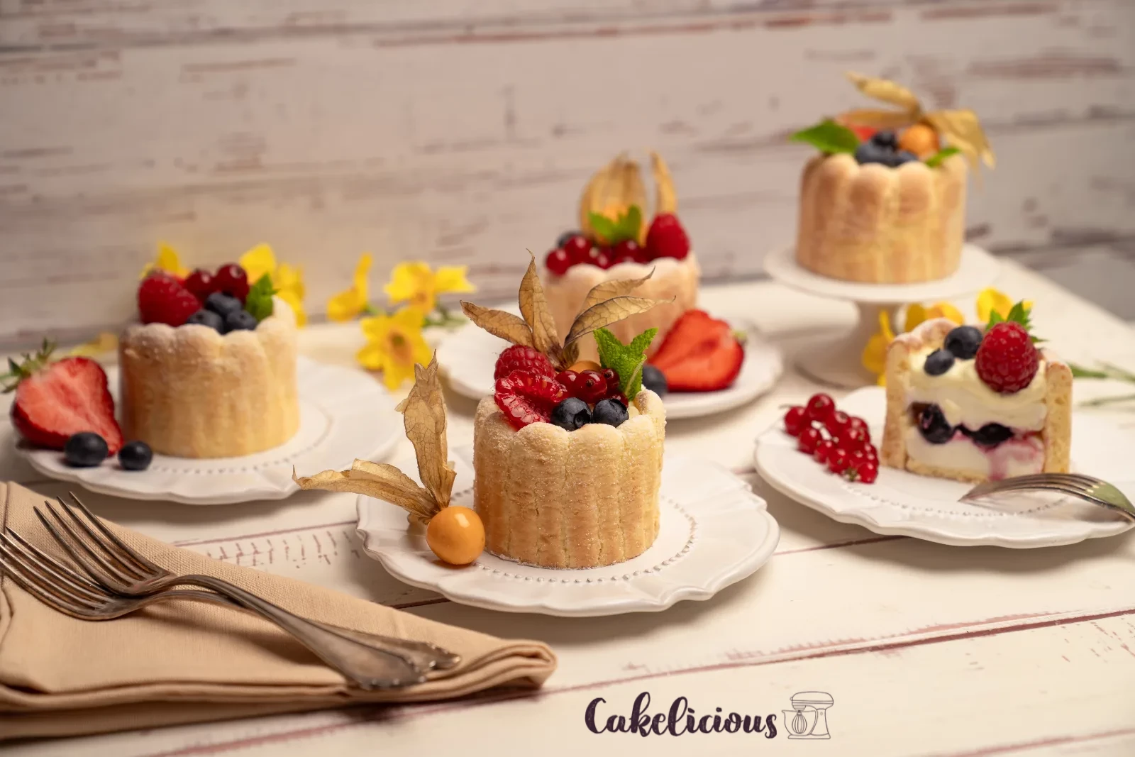 Row of finished charlottes on a stand, with a bowl of mixed berries in the background