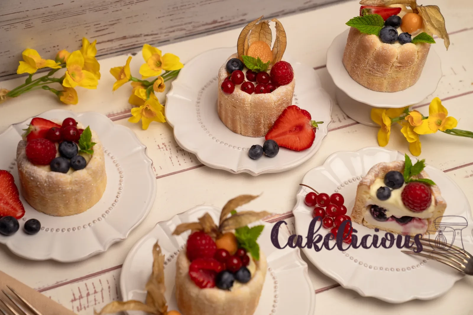 Row of finished charlottes on a stand, with a bowl of mixed berries in the background