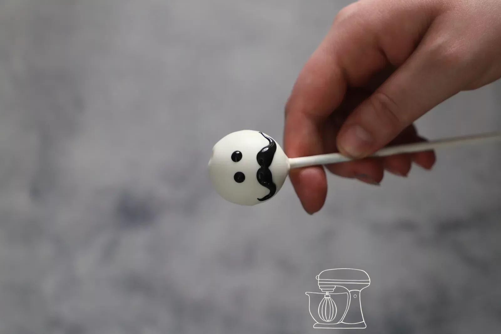 Weisser Cake Pop mit gemaltem Gesicht