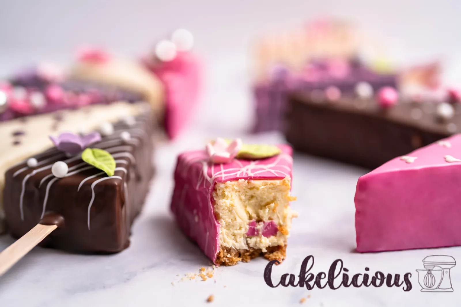 Dodici pezzi di cheesecake glassati su stecco, disposti in cerchio sul marmo