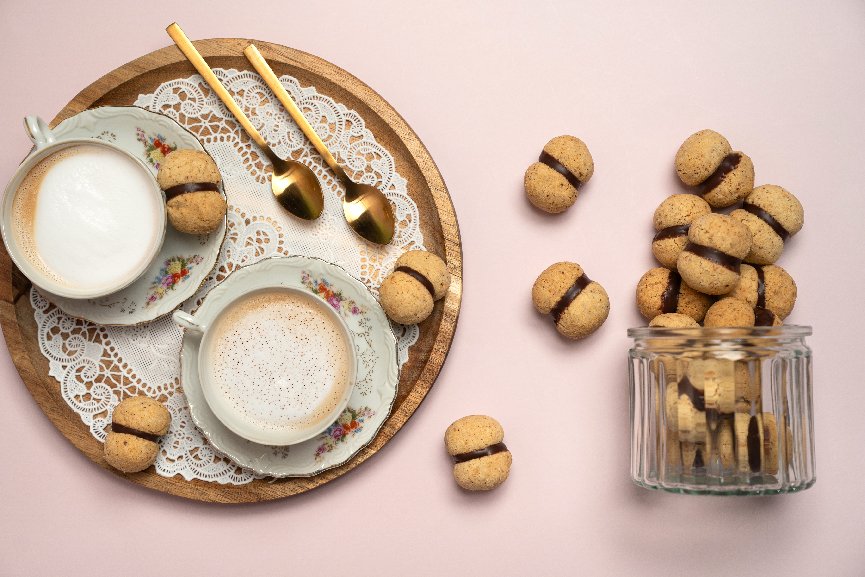 Baci di Dama avec café et boîte en verre sur fond rose, vus du dessus