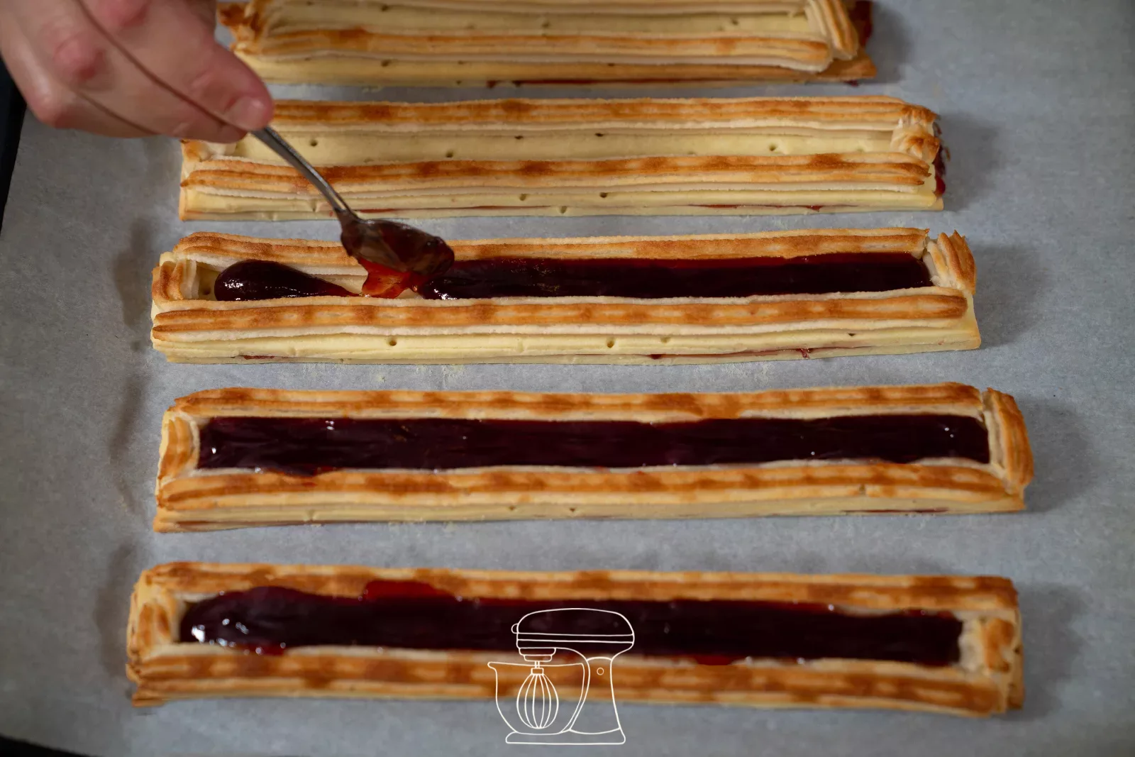 Close-up: jam being placed into the groove between the almond strips