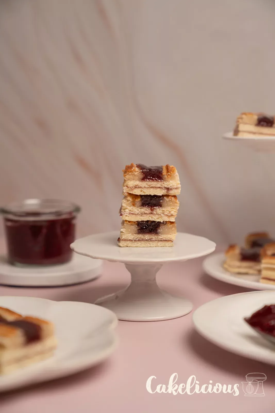 Stacked railway worker cookies on a small cake stand, with a filled tiered stand behind