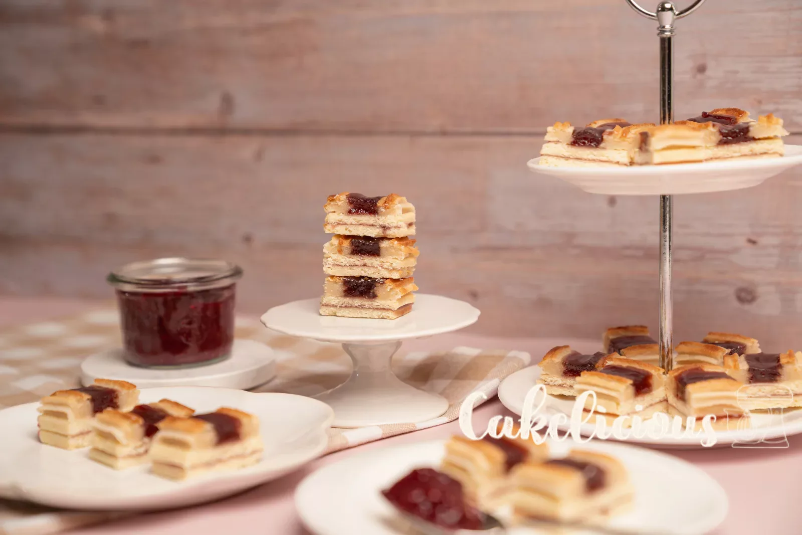 A single railway cookie on a mini cake stand, with a plate of more cookies behind it