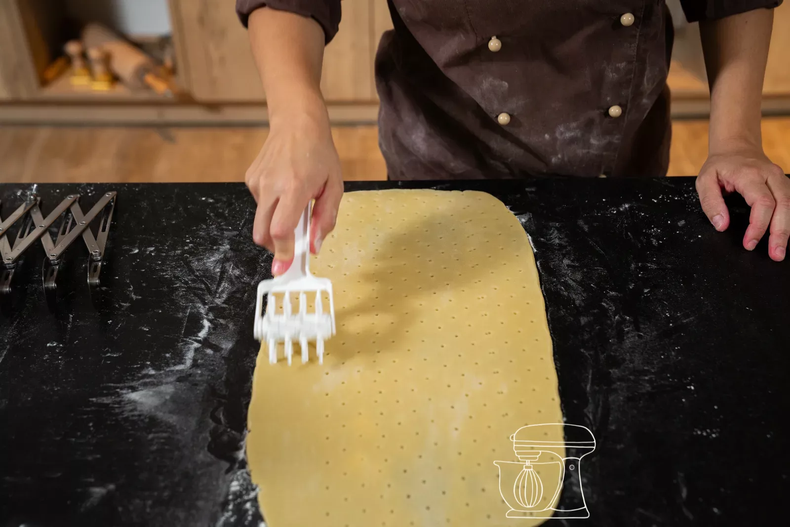Rolled-out shortcrust pastry is pricked with a mini roller docker
