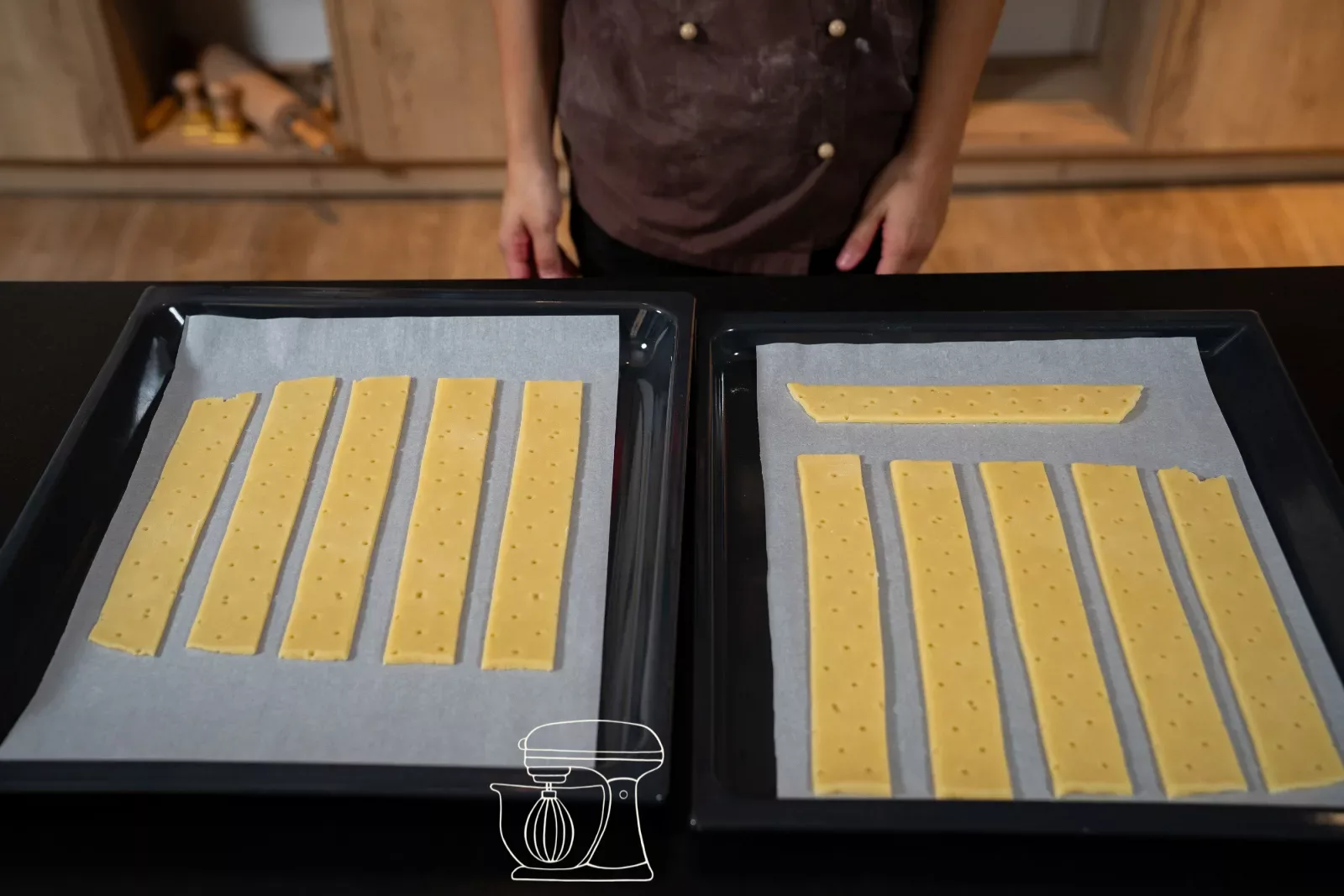 Twelve strips of shortcrust pastry lie straight on two baking trays lined with baking paper