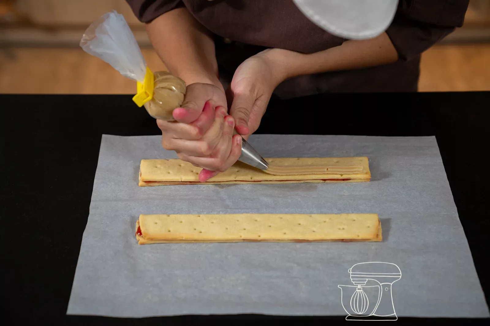 Almond paste being piped along the edge of a dough strip with the Piping bag