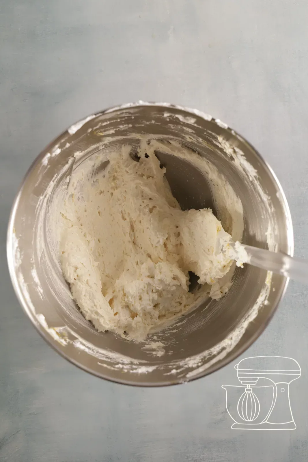 Financier mixture being gently folded in with a dough scraper