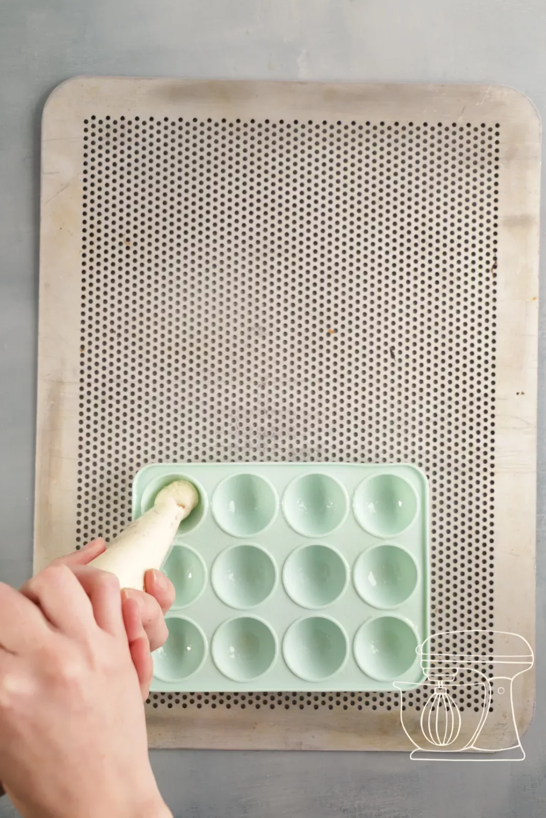 Financier batter being piped into the cavities of the cake pop baking tin