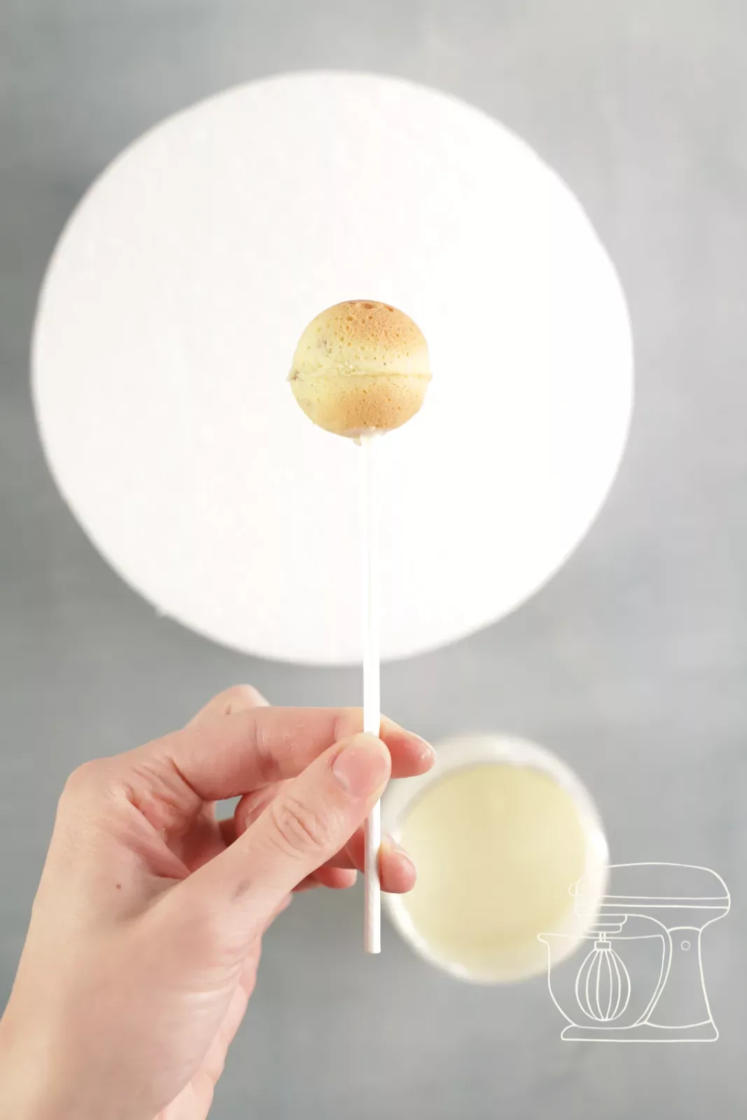Cake pop stick being dipped into melted Deco melts