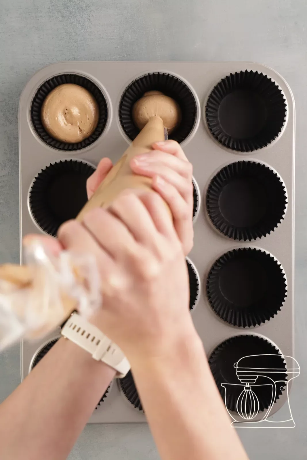 Schwarze Metallic-Cupcakeförmchen zu drei Vierteln mit Teig gefüllt