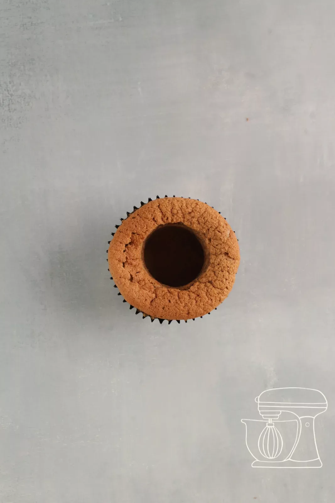 Ausgehöhlter Cupcake mit einem Teigstück auf dem Boden