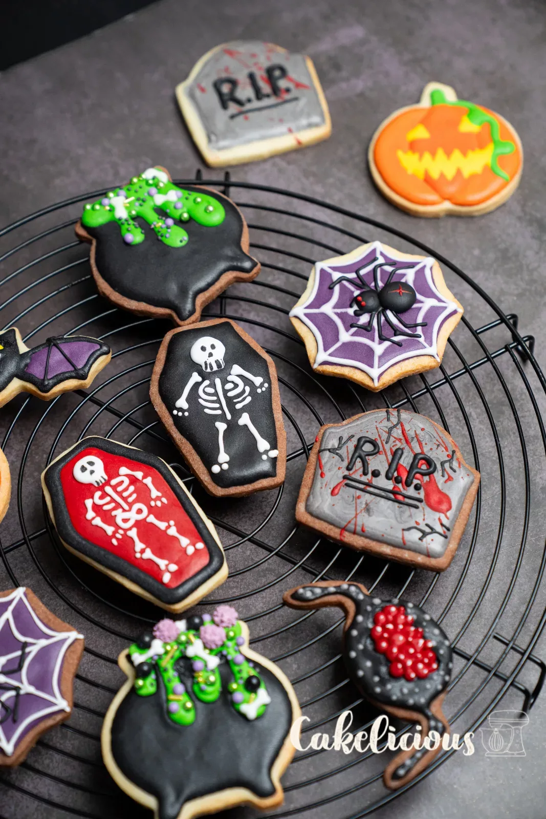 Halloween-Guetzli mit Grabstein, Kessel und Skelett auf einem Gitter