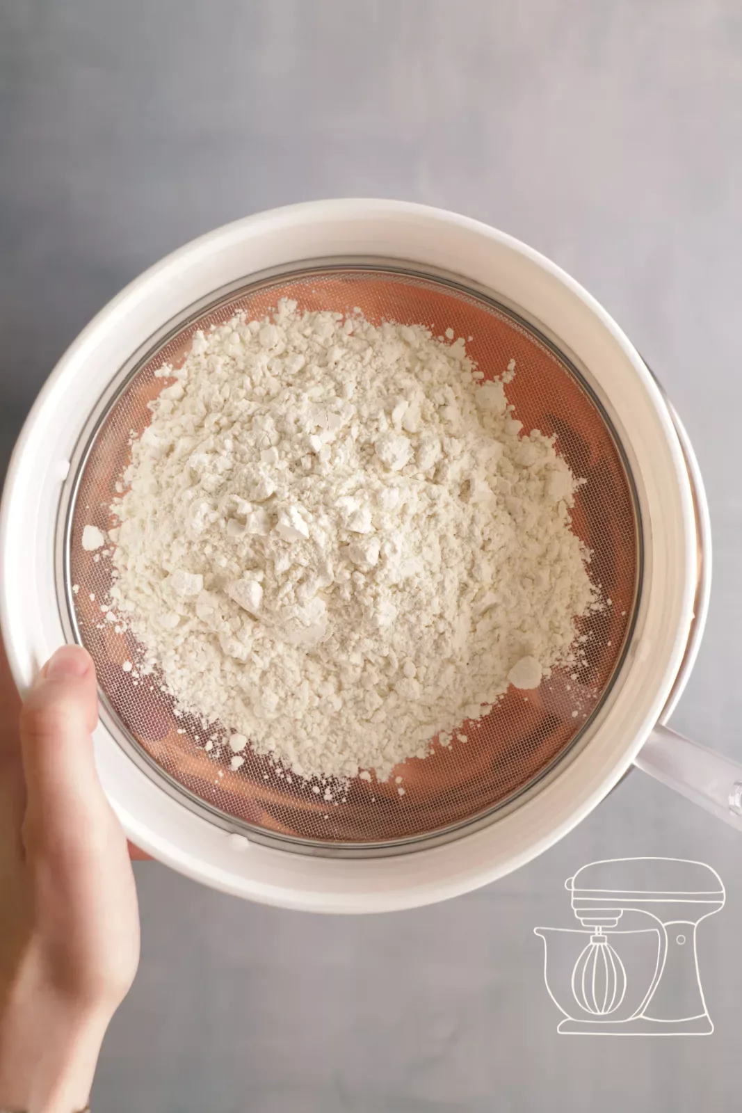 Flour being sieved through a Sieve over the sponge mixture