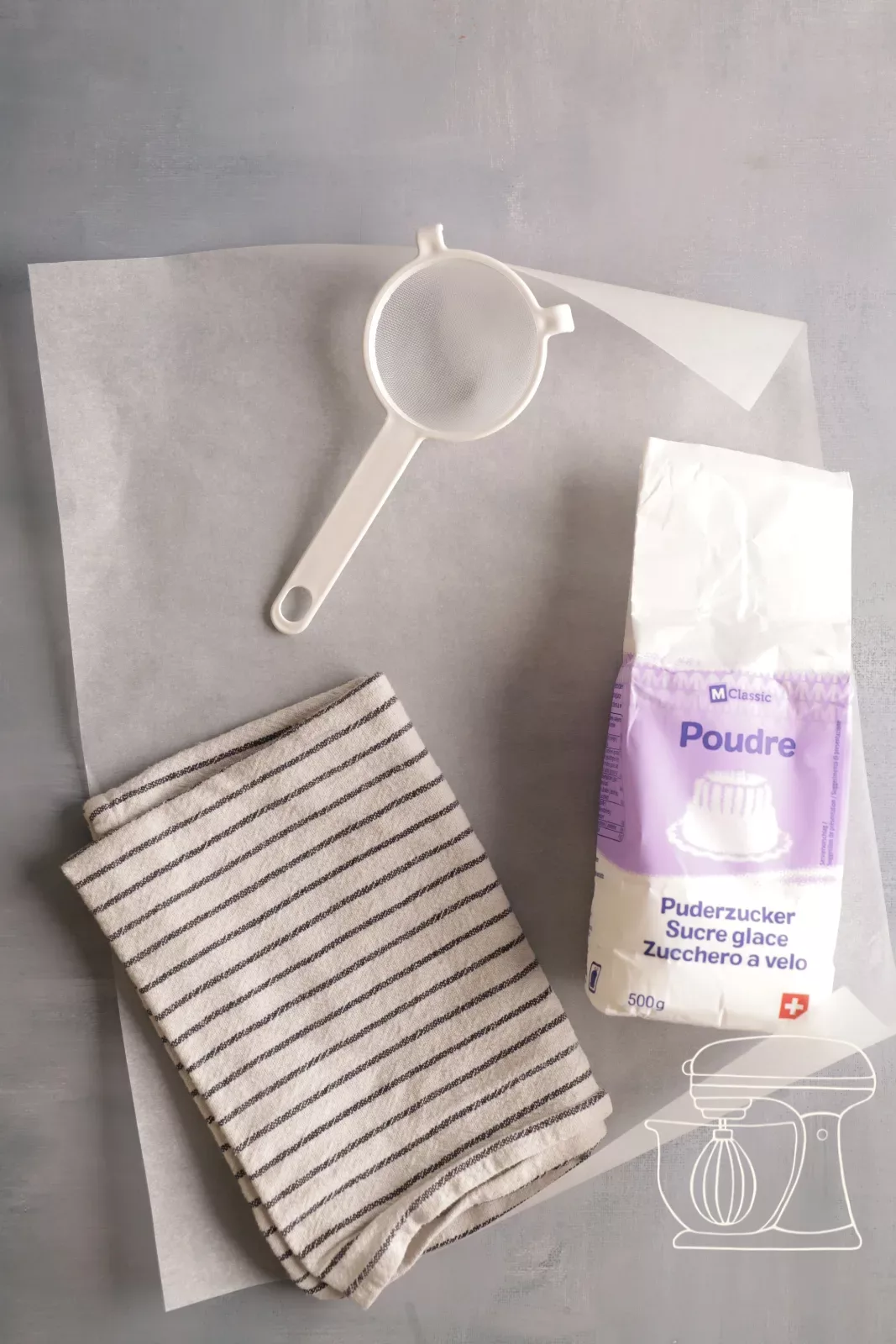 Baking paper being sprinkled with icing sugar