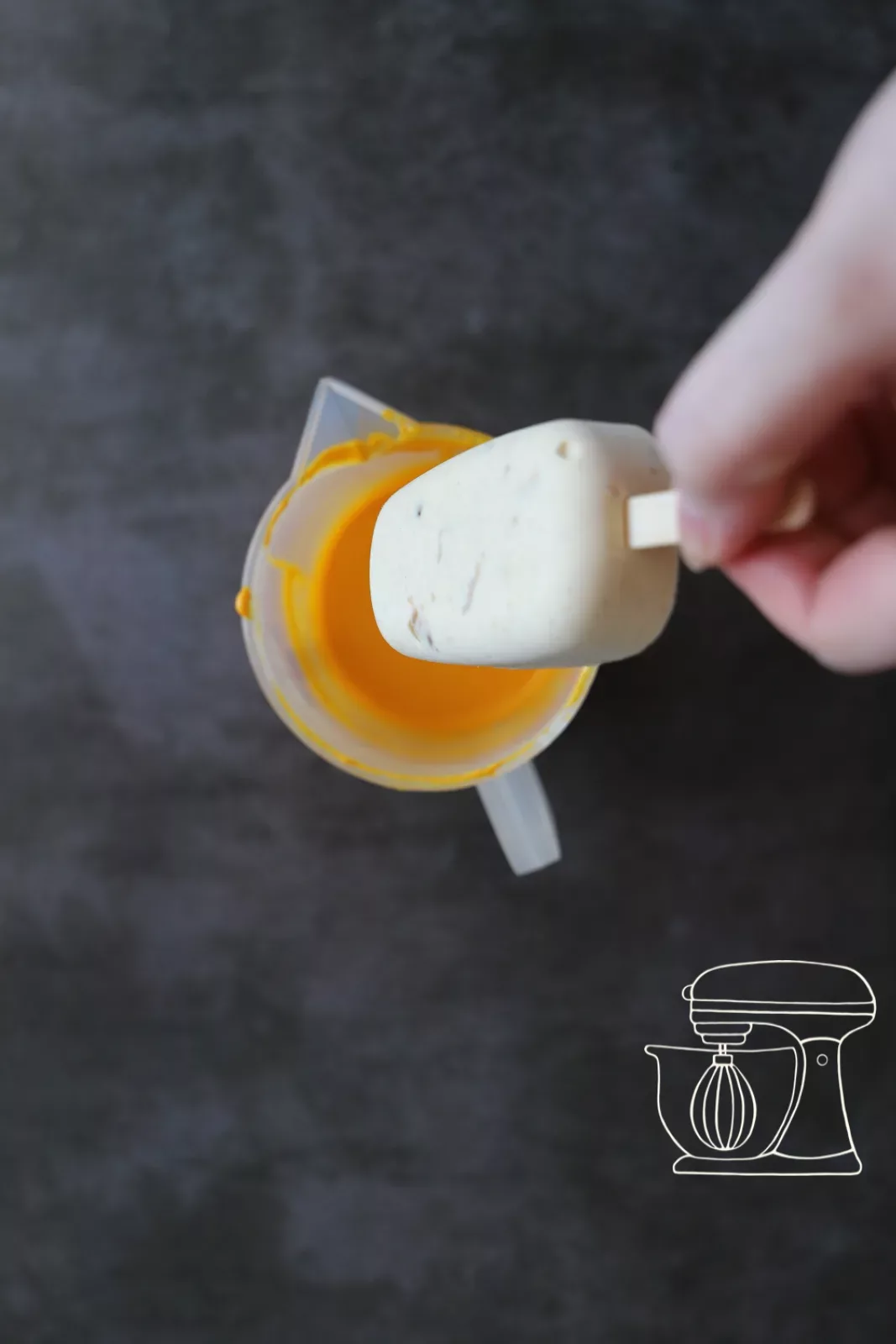 Cakesicle being dipped by the stick into the Deco melts