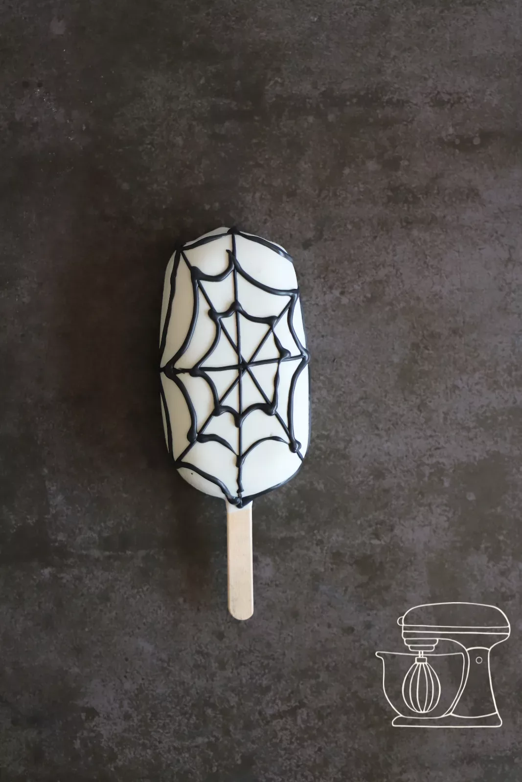 Spider web being piped onto the cakesicle with Deco melts
