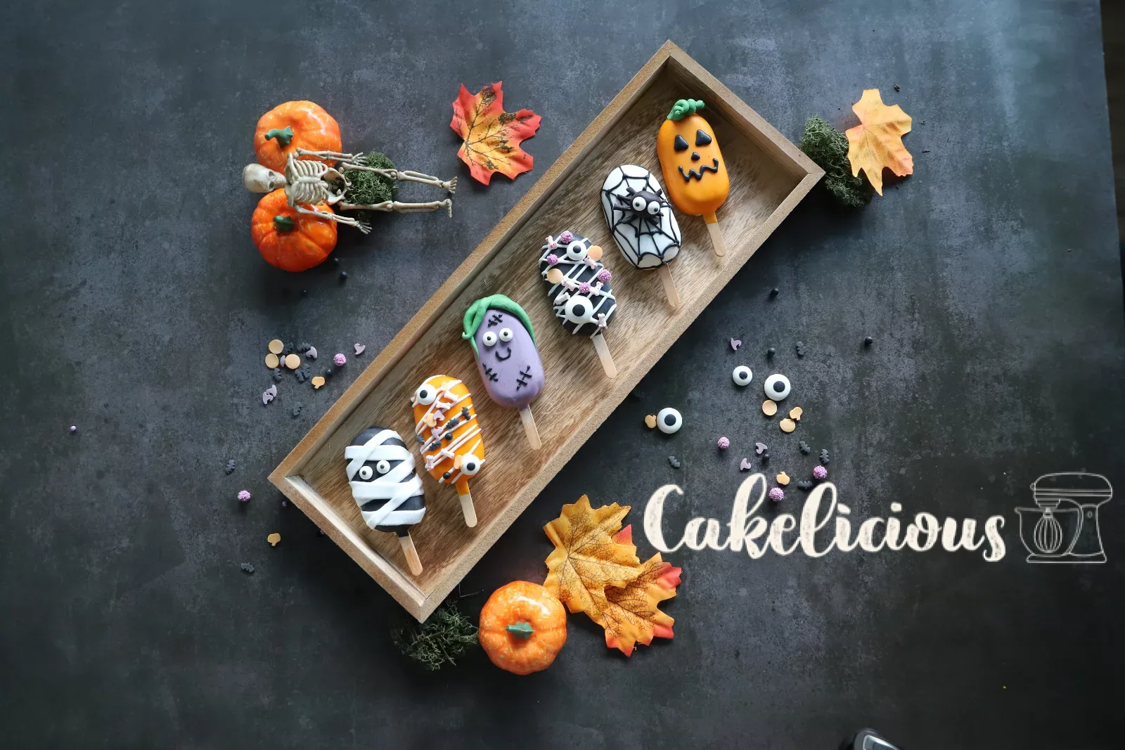 Halloween cakesicles decorated as a pumpkin, mummy, zombie and spider