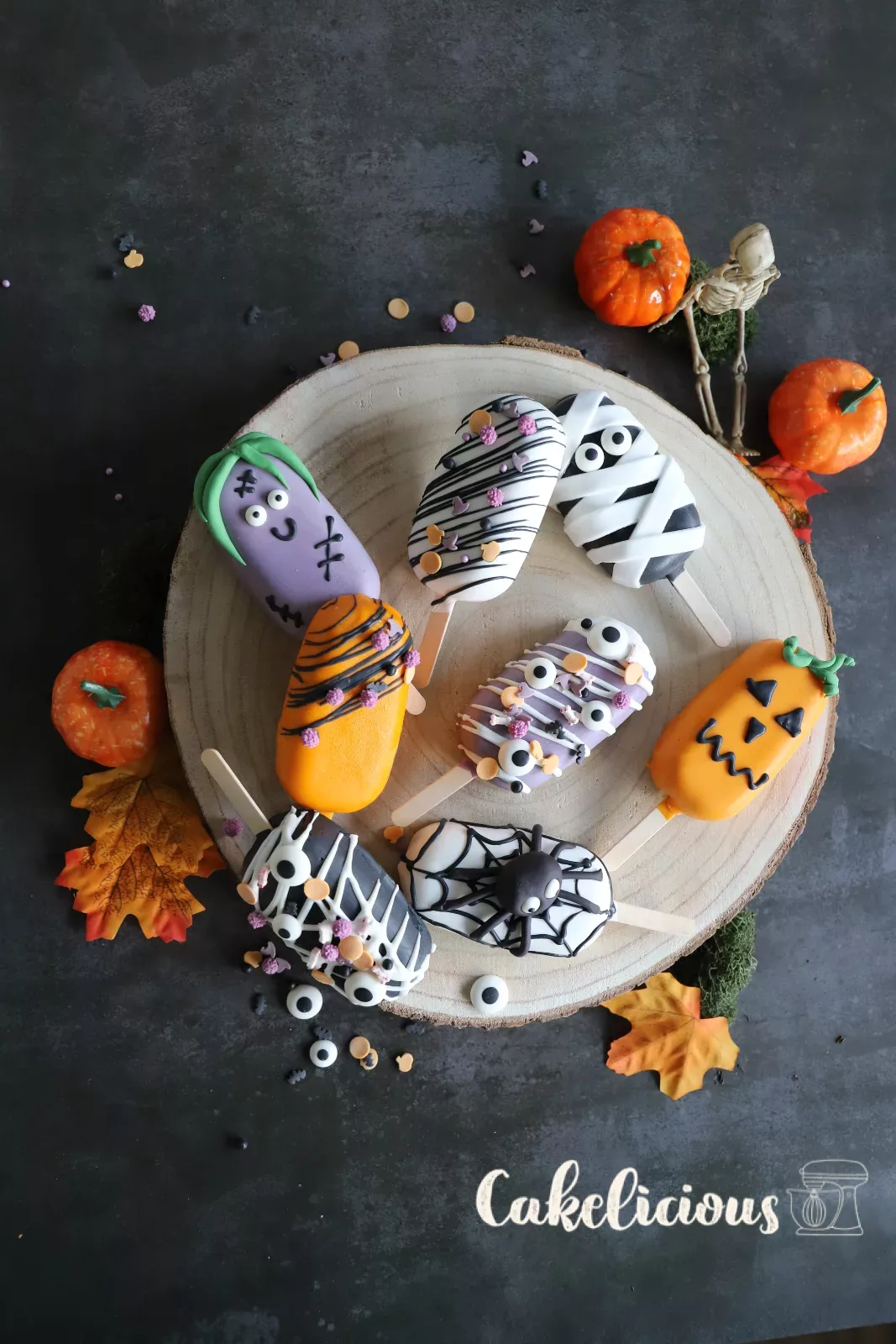 Halloween cakesicles decorated as a pumpkin, mummy, zombie and spider