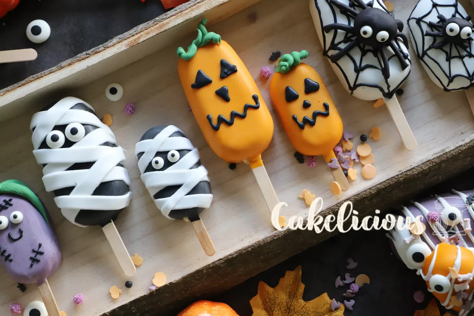 Halloween cakesicles decorated as pumpkin, mummy, zombie and spider