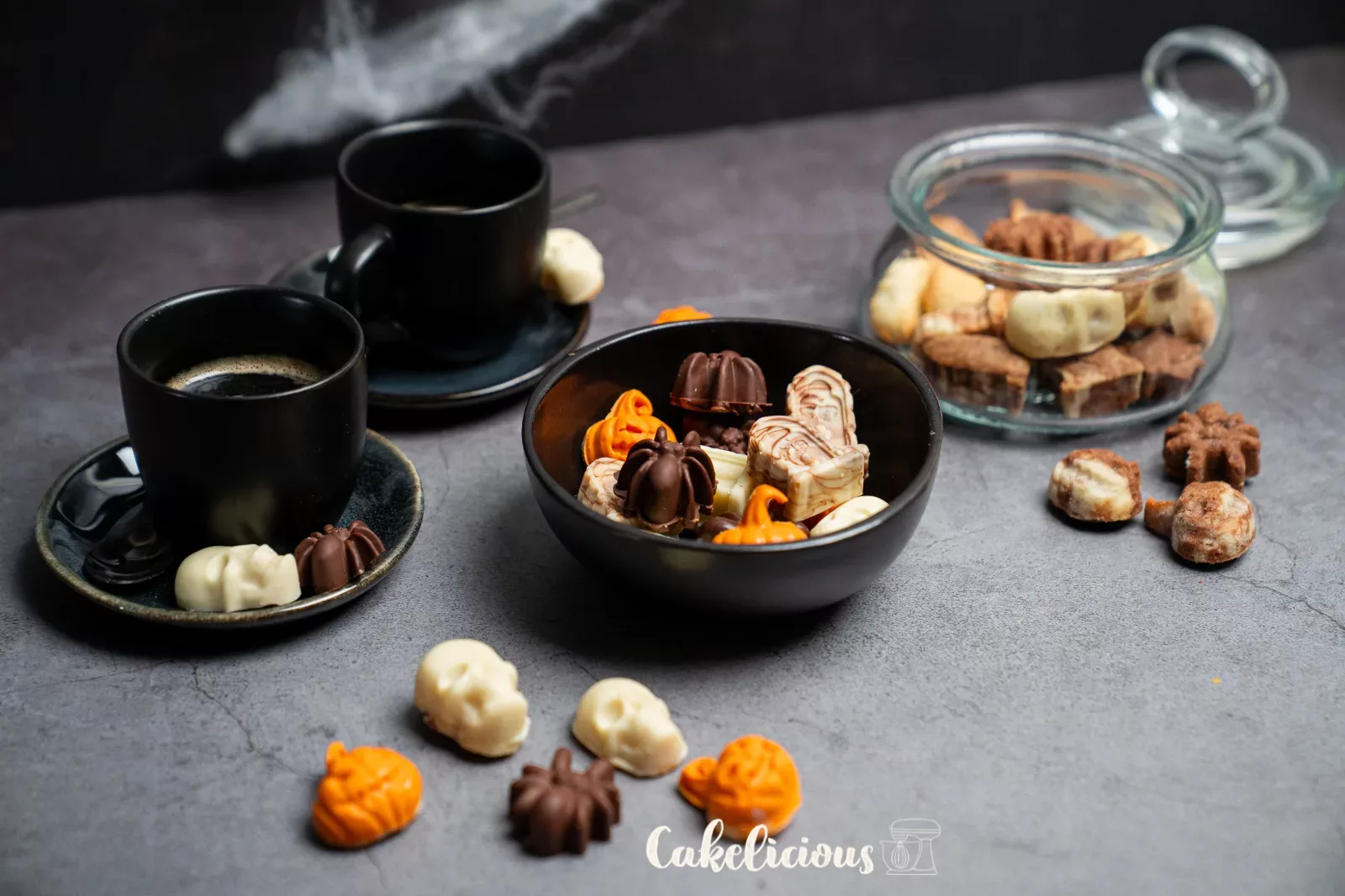 Schale mit Halloween-Guetzli und Zange, daneben Totenköpfe und Kürbisse