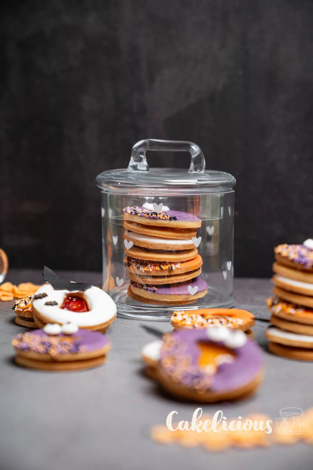 Biscotti Spitzbuben di Halloween impilati accanto a un bicchiere