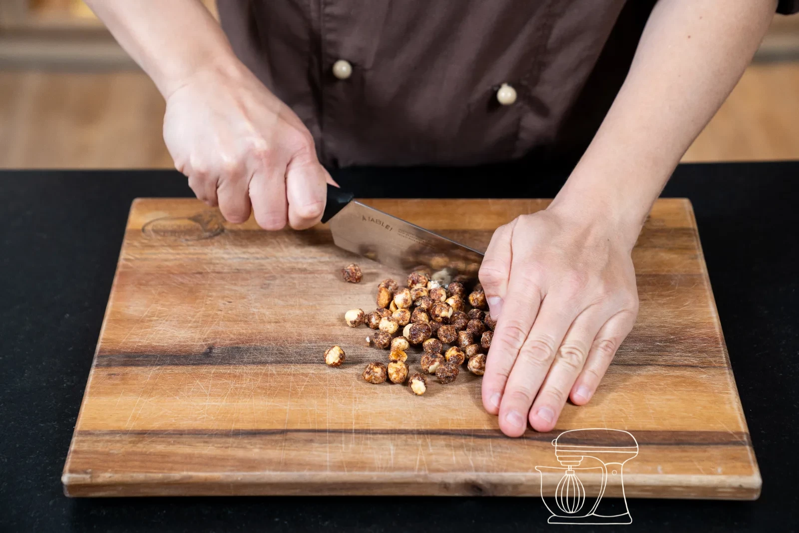 Caramelised hazelnuts being chopped coarsely on the wooden board