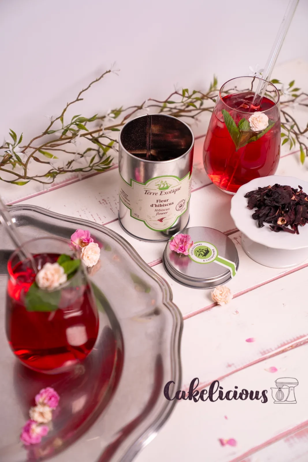 Un bicchiere di tè freddo all'ibisco con cannuccia di vetro, foglia di menta e petalo di rosa essiccato