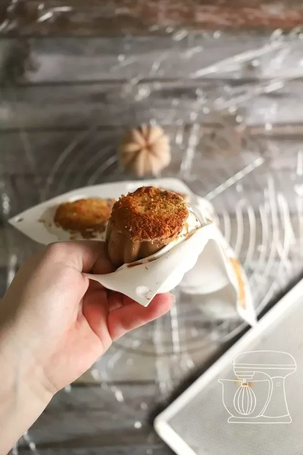 Frozen mousse pumpkins on a cake rack over cling film