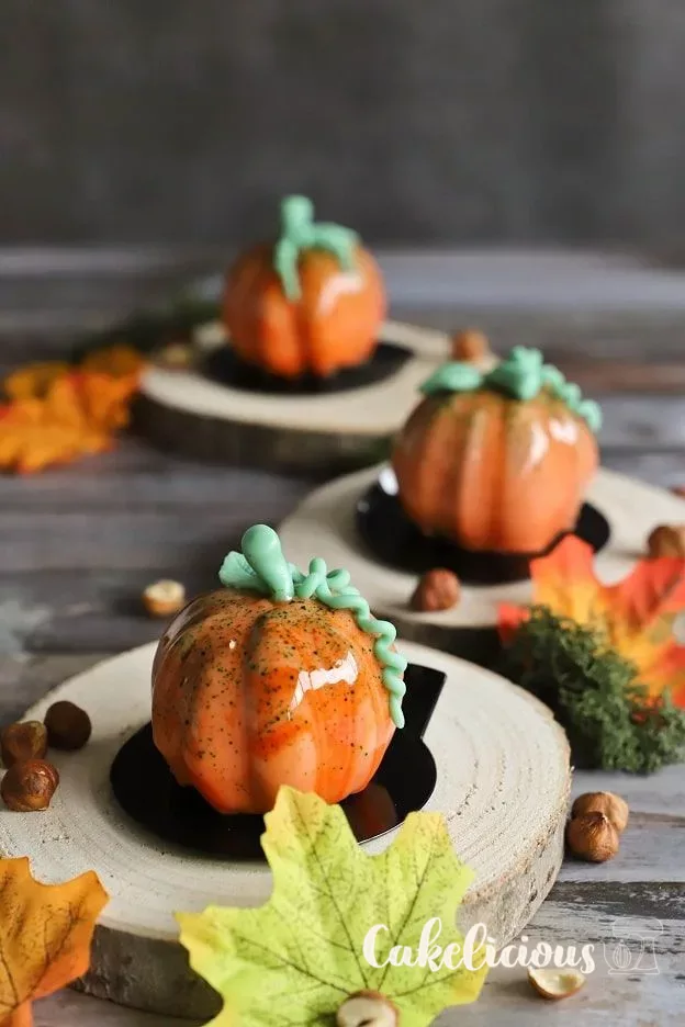 Pumpkin mousse tartlets with orange mirror glaze and stems made of Modeling chocolate
