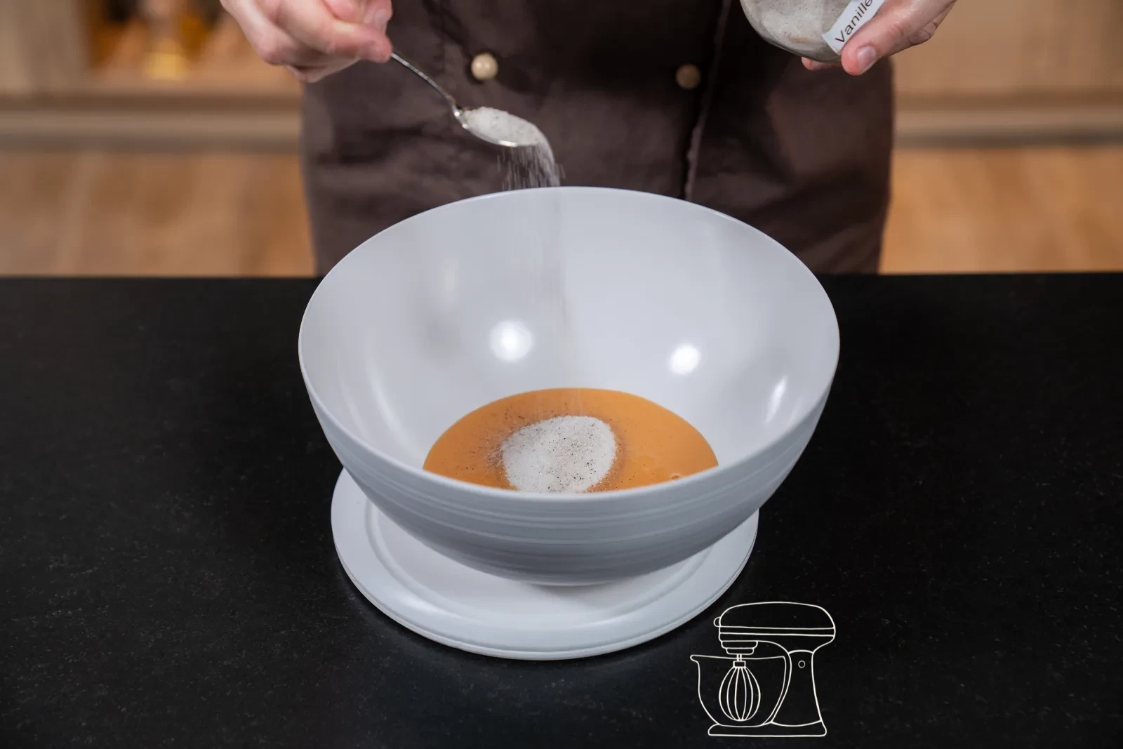 Pale and thickly whisked egg mixture with sugar on the whisk of the stand mixer