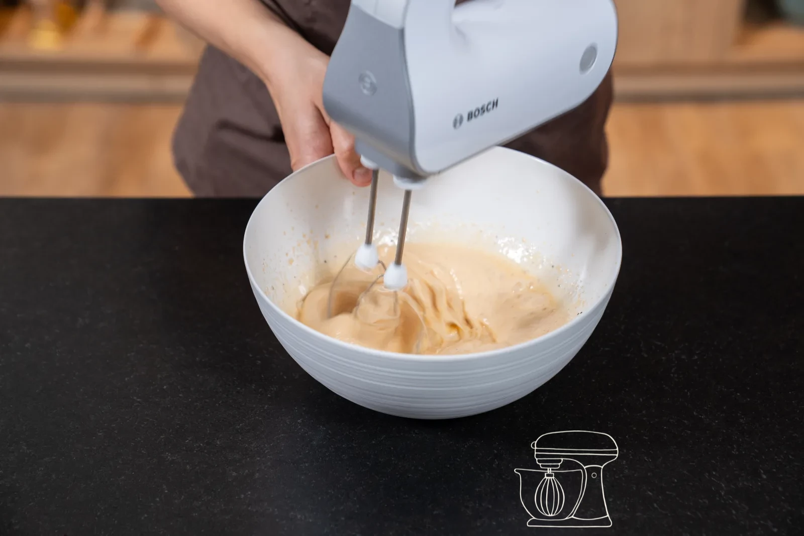Pale and thickly whisked egg mixture with sugar on the whisk of the stand mixer